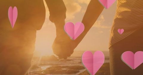 Romantic Couple Holding Hands with Heart Icons Overlay at Sunset