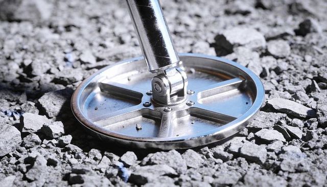 Metal detector search coil closeup on gravel showing bolts hinge tubular shaft macro