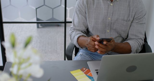 Man Texting on Smartphone at Office Desk with Laptop and Color Swatches - Download Free Stock Images Pikwizard.com