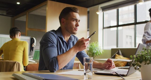 Focused Businessman Working in Modern Office Holding Pen - Download Free Stock Images Pikwizard.com