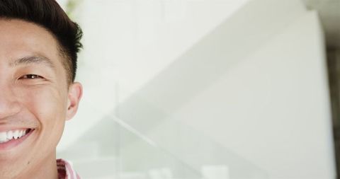 Close-Up of Smiling Young Asian Man Indoors with Blank Space