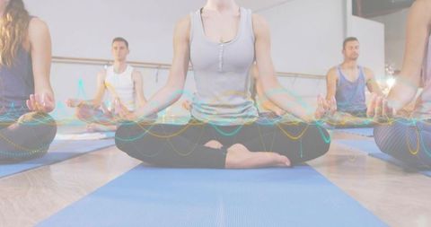 Group practicing yoga meditation on blue mats with colorful waveform overlay