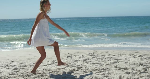 Happy woman enjoying a sunny day walking along the seashore. Ideal for summer vacation, beach lifestyle, relaxation, and travel promotions. Can be used for wellness, fitness, outdoor activities, and holiday ads showing a carefree and active beach lifestyle.