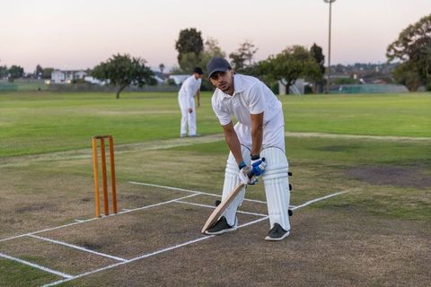 Indian batsman preparing to face bowler at dusk standing in crease wearing full white kit