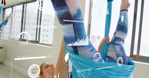 Aerial yoga athlete performing inverted silk hammock pose in urban studio with hud overlay