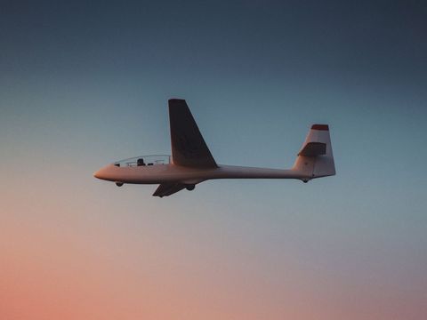 Glider soaring against a colorful sunset sky