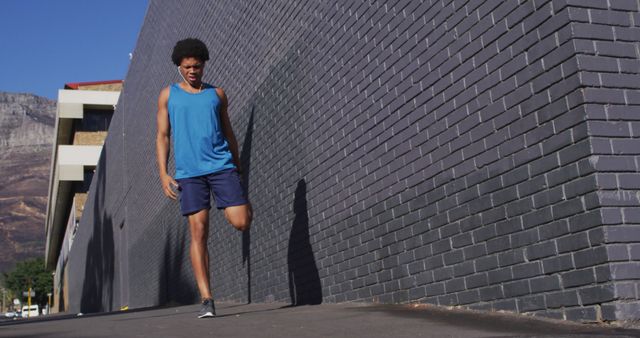 Young Man Warming Up Before Jogging Near Urban Brick Wall - Download Free Stock Images Pikwizard.com