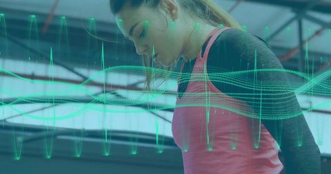 Woman tracking fitness data with in-ear earbuds at gym