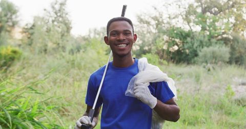 Smiling volunteer cleaning river holding rubbish bag