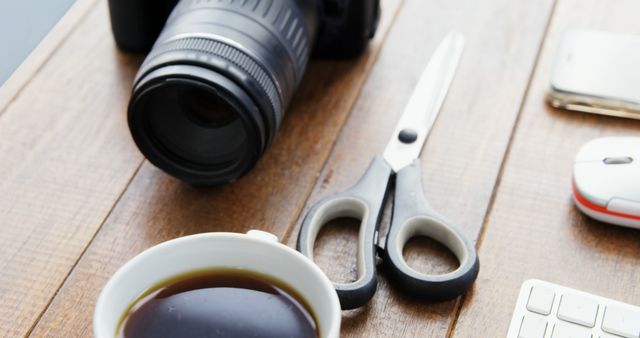 Items like a coffee cup, camera, scissors and office tools on a work table. Suitable for illustrating modern workspaces, office productivity, creative work environment, and freelance lifestyle.