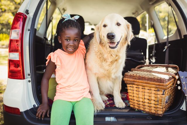 Young girl sitting with her golden retriever in car trunk, ready for a picnic. Ideal for themes of family outings, pet companionship, summer adventures, and outdoor activities. Perfect for use in advertisements, blogs, and social media posts promoting family fun, travel, and pet-friendly activities.