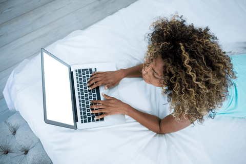 Curly-haired woman using laptop with transparent screen at home