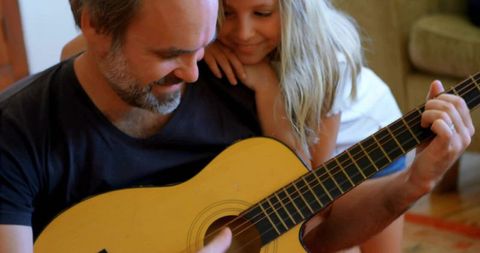 Father and Daughter Playing Acoustic Guitar Together at Home