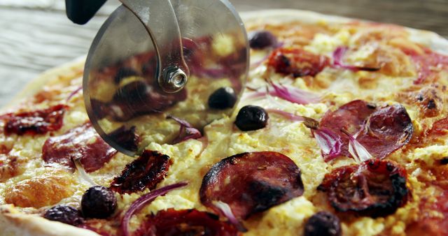 Slicing a freshly cooked homemade pizza with toppings including pepperoni, black olives, red onions, and cheese. Perfect for culinary blogs, recipe websites, or advertisements promoting kitchen tools and pizza restaurants.