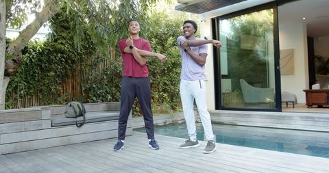 Confident diverse friends stretching near pool outdoors