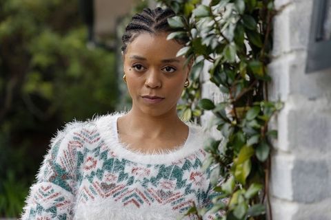 African american woman in fuzzy patterned sweater with gold hoops by ivy-covered brick wall