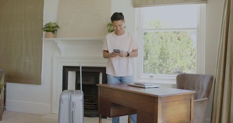 Young man organizing travel plans in modern living room with laptop