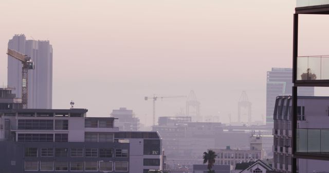 Dense urban landscape during twilight with construction cranes amidst modern buildings. Ideal for use in articles, advertisements, and presentations focusing on urban development, modern architecture, real estate, and city life themes.