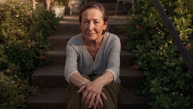 Thoughtful senior woman sitting on garden steps during golden hour, relaxed lifestyle portrait