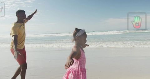 Father and daughter running and spinning on beach shoreline, playful family moment