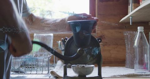 Vintage hand-crank coffee grinder on wooden counter in sunlit rustic kitchen