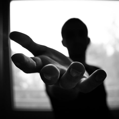 Silhouette of person reaching hand forward in black and white