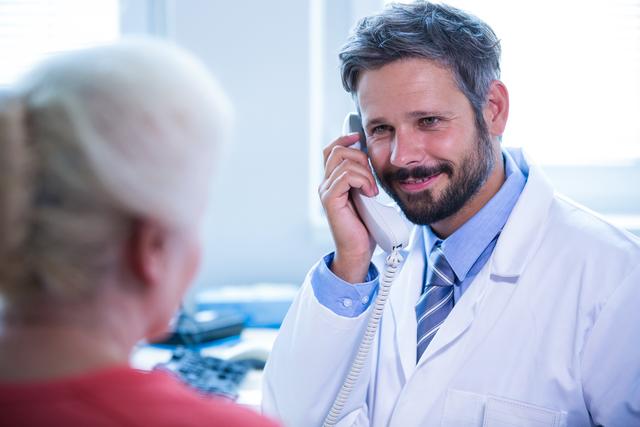 Smiling doctor talking on landline phone in medical office at hospital