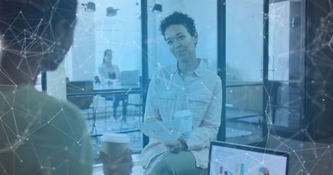 Businesswoman in modern office analysing documents with digital network overlay