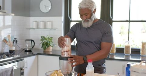Senior African American Man Making Smoothie in Modern Kitchen