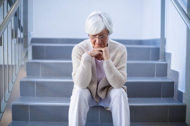 Upset senior woman sitting on stairs in hospital