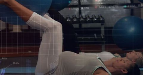 Two women performing stability ball core workout with data overlay in gym