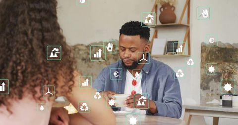Man holding cup and saucer in cozy cafe with woman and floating green icons, wearing blue shirt