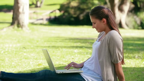 Young Woman Relaxing on Grass Using Laptop in Park