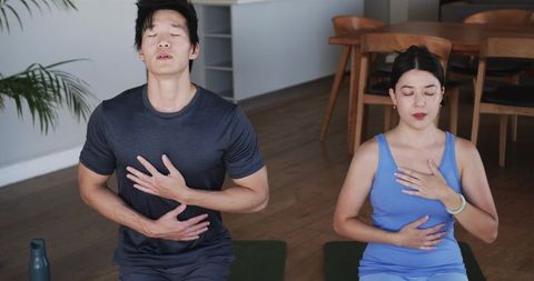 Couple practicing guided breathwork on yoga mats for mindfulness and stress relief at home