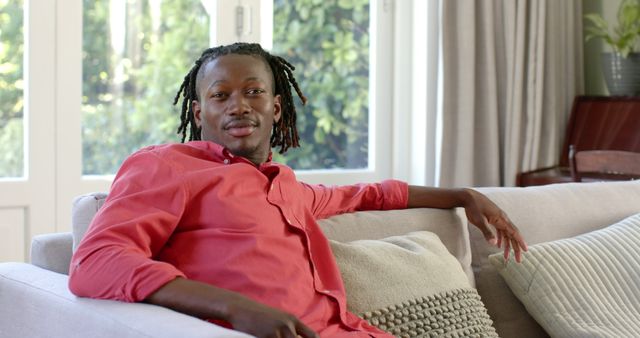 Smiling Young Black Man Relaxing on Couch at Home in Casual Red Shirt - Download Free Stock Images Pikwizard.com