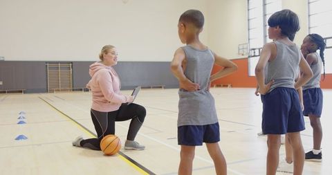 Coach Guiding Young Team Through Basketball Drills in Gym