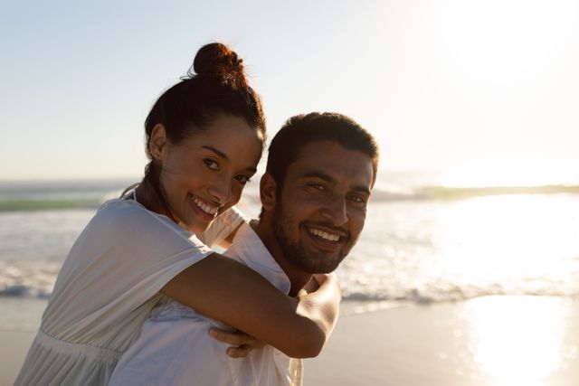 Portrait of man giving piggyback ride to woman on the beach