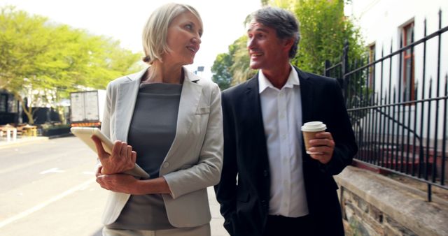 Smiling Businesspeople Walking Outside with Coffee and Tablet - Download Free Stock Images Pikwizard.com