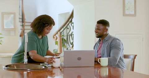 Couple Reviewing Documents Over Coffee with Laptop in Modern Home