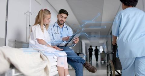 Doctor Demonstrating Tablet to Young Patient in Hospital Corridor