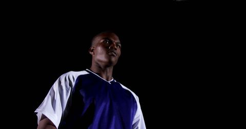 Determined athlete in sports jersey under dark sky