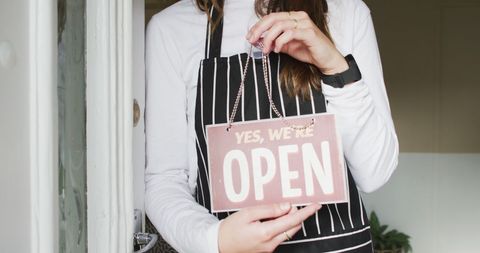 Waitress holding open sign at cafe doorway