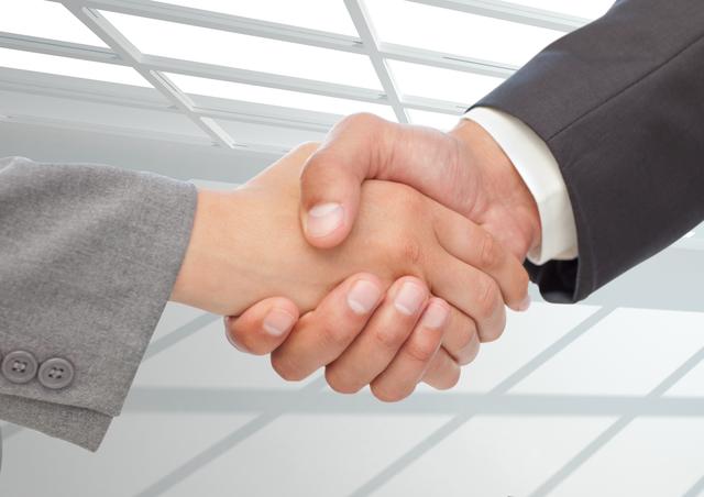 Business handshake symbolizing agreement and partnership in a modern office environment. Ideal for use in corporate presentations, business websites, and marketing materials to convey themes of collaboration, trust, and professional success.