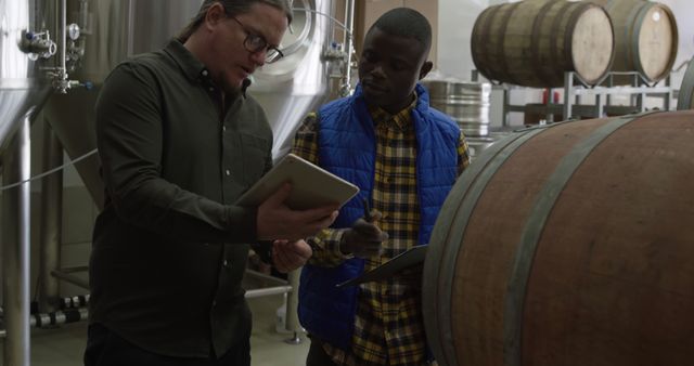 Brewer Instructing Colleague in Brewery with Tablet and Clipboard - Download Free Stock Images Pikwizard.com