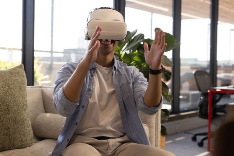 Asian Man Engaging with Virtual Reality in Modern Office Lounge