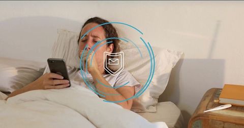 Mid adult woman resting in bed checking smartphone for updates