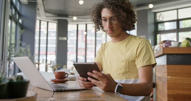 Young man reading tablet while working in trendy cafe - Download Free Stock Images Pikwizard.com