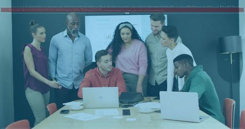 Diverse team collaborating around laptops in conference room for brainstorming and planning