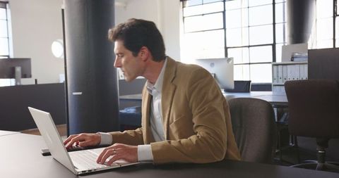 Business Professional Focused on Laptop Work in Modern Office