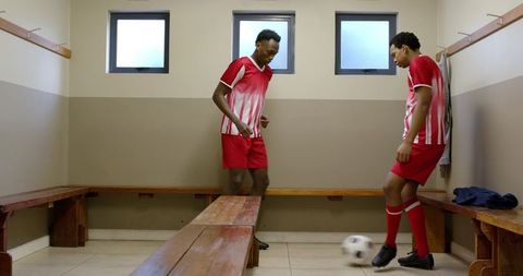 Athletic teammates practicing soccer skills in locker room